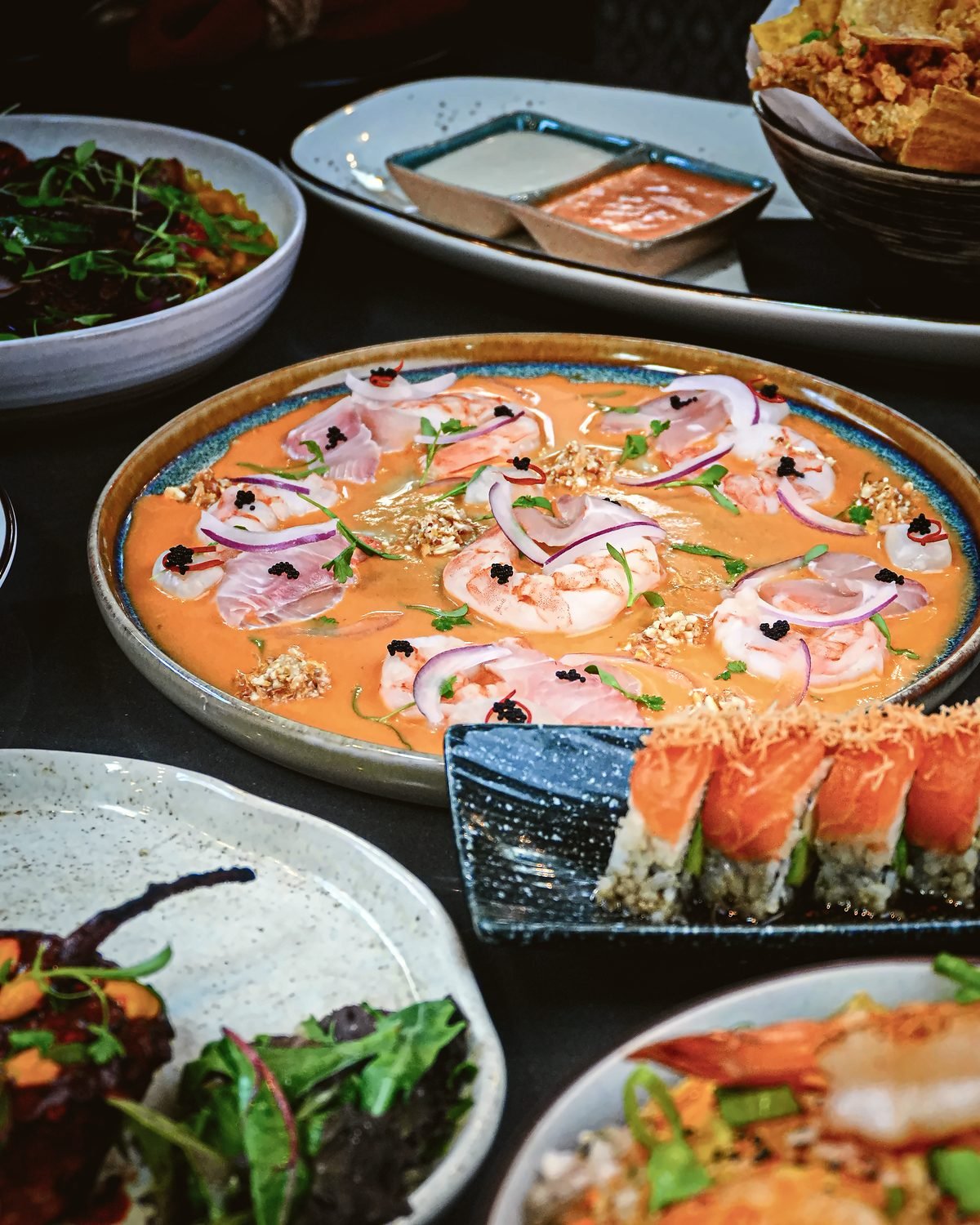 Una mesa de platos nikkei de Killa: cebiche con langostinos, maki y entradas